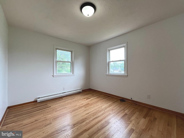 unfurnished room featuring light wood-style floors, baseboards, a baseboard radiator, and a wealth of natural light