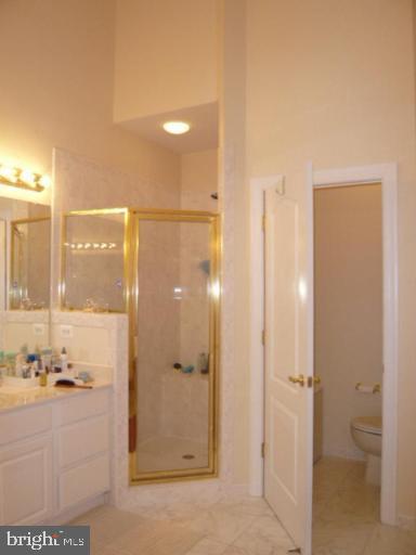bathroom with vanity, tile patterned floors, a stall shower, and toilet