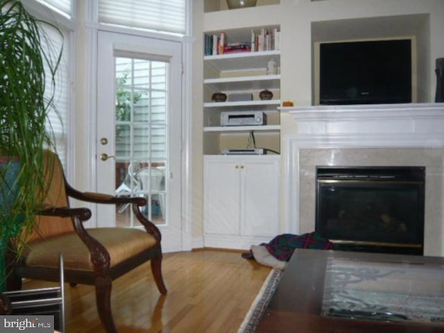 interior space with built in features, wood finished floors, and a premium fireplace