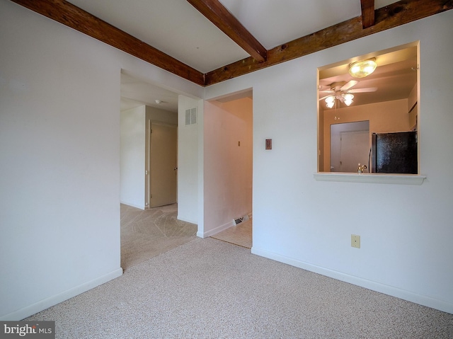 carpeted empty room with beamed ceiling, a ceiling fan, and baseboards