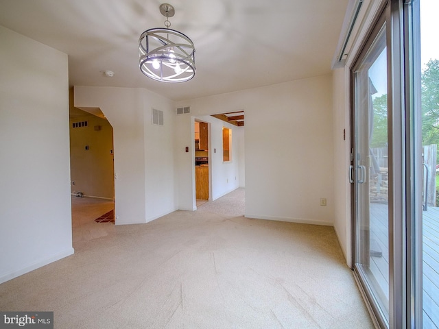 empty room with carpet, visible vents, baseboards, and a notable chandelier