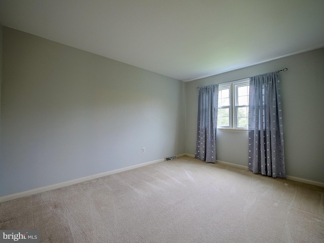 carpeted empty room featuring baseboards and visible vents