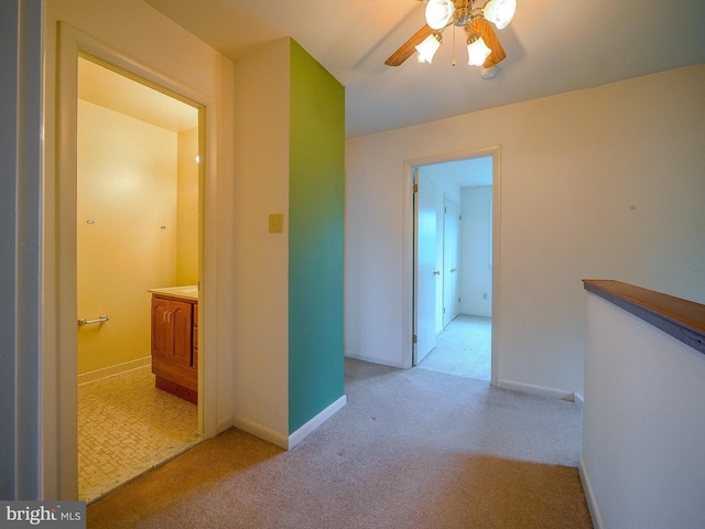 hallway with an upstairs landing, baseboards, and carpet floors