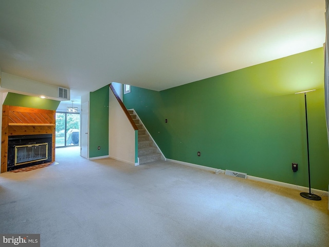 unfurnished living room featuring a glass covered fireplace, carpet flooring, and visible vents