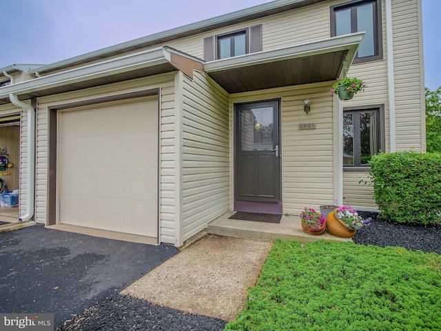 doorway to property featuring an attached garage and driveway