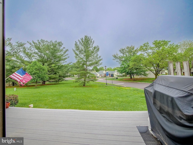 wooden deck with a yard and a grill