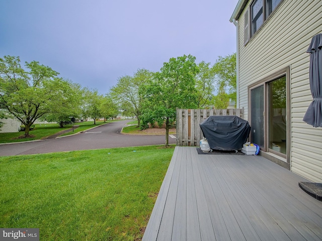 wooden terrace featuring a lawn and grilling area