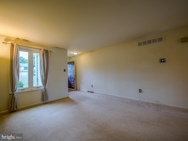 spare room with baseboards, light carpet, and visible vents