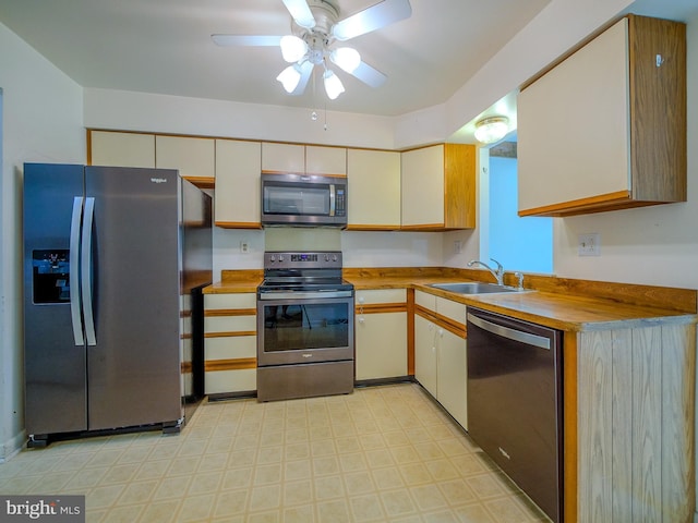 kitchen featuring appliances with stainless steel finishes, light floors, a ceiling fan, and a sink