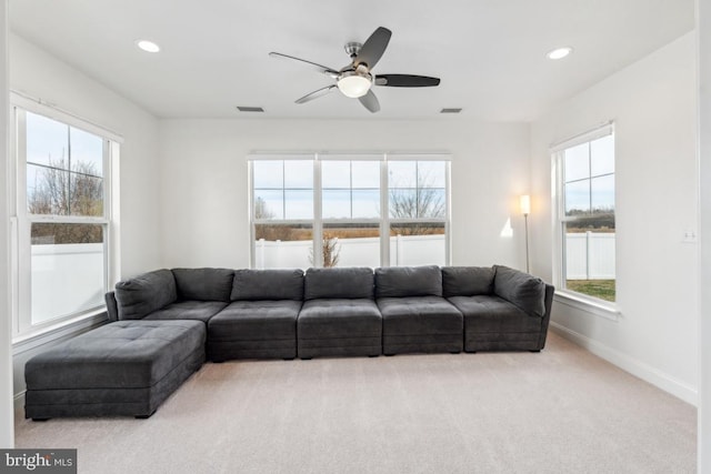 living room with carpet floors, a ceiling fan, visible vents, and a healthy amount of sunlight