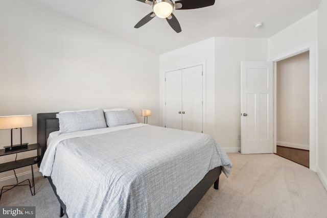 bedroom with light colored carpet, a ceiling fan, baseboards, and a closet