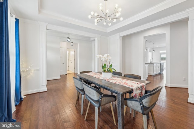 dining area featuring crown molding, decorative columns, baseboards, dark wood-type flooring, and a notable chandelier