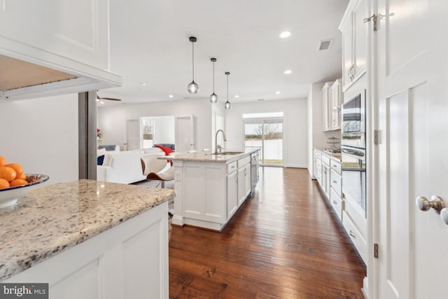 kitchen featuring appliances with stainless steel finishes, a sink, white cabinetry, open floor plan, and visible vents