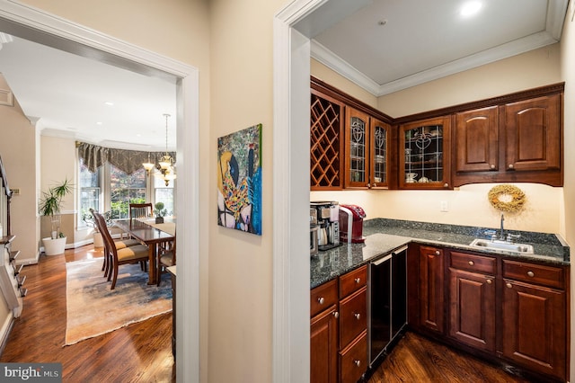 bar featuring a sink, dark wood finished floors, crown molding, a chandelier, and baseboards