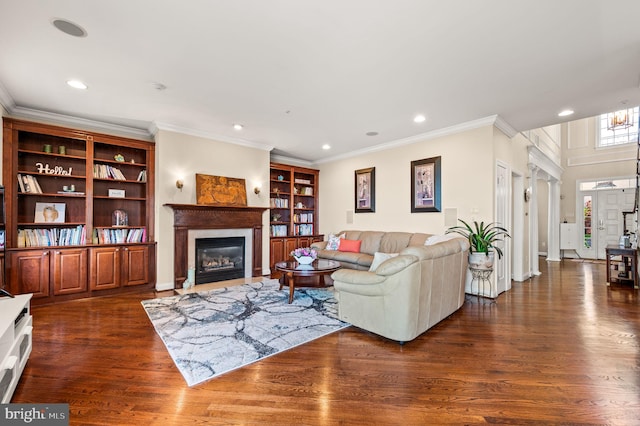 living area with dark wood finished floors, recessed lighting, a glass covered fireplace, and crown molding