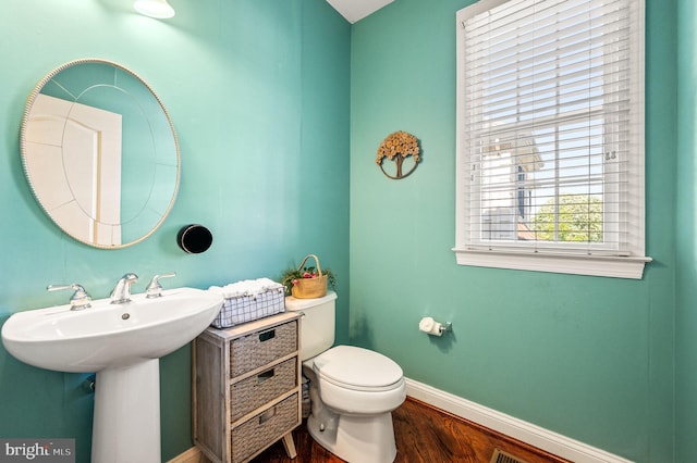 half bathroom featuring baseboards, wood finished floors, toilet, and a sink