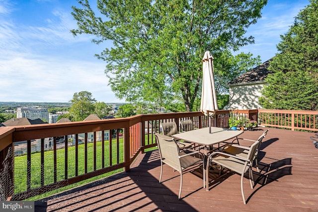 wooden deck with outdoor dining space and a yard