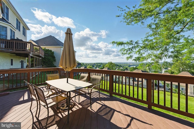 wooden deck with outdoor dining space and a lawn