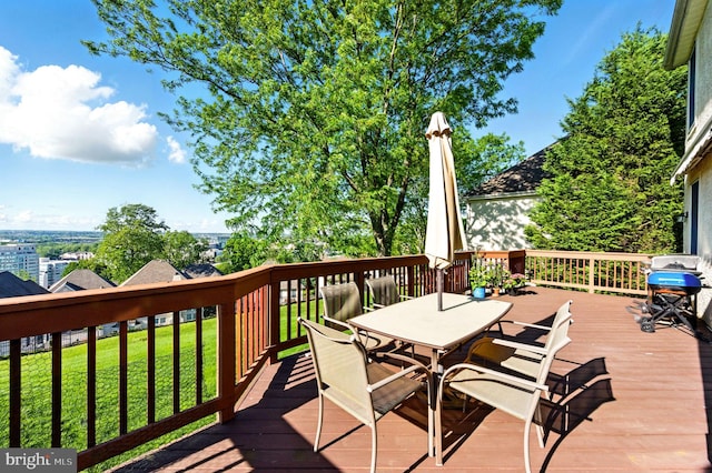 wooden terrace featuring outdoor dining area and a yard