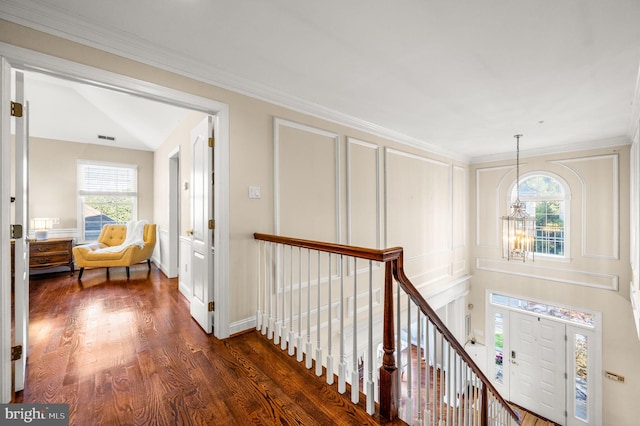 corridor with an upstairs landing, a chandelier, dark wood-type flooring, and crown molding