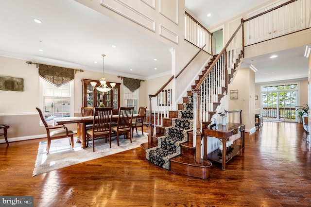 stairway with crown molding, wood finished floors, baseboards, and recessed lighting