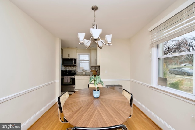 dining room with baseboards, an inviting chandelier, and light wood-style flooring
