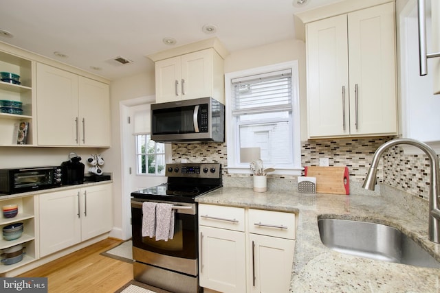 kitchen featuring a sink, open shelves, stainless steel appliances, and a toaster