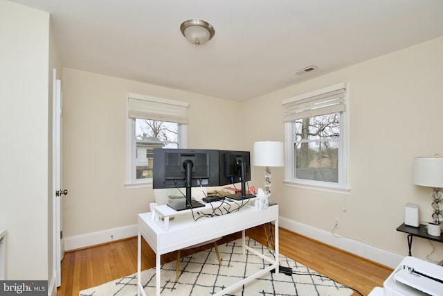 office area with baseboards, wood finished floors, and visible vents