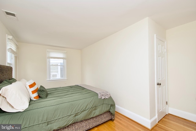 bedroom featuring baseboards, wood finished floors, and visible vents