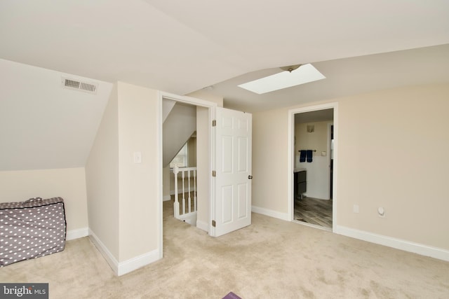 additional living space with carpet flooring, baseboards, visible vents, and lofted ceiling with skylight