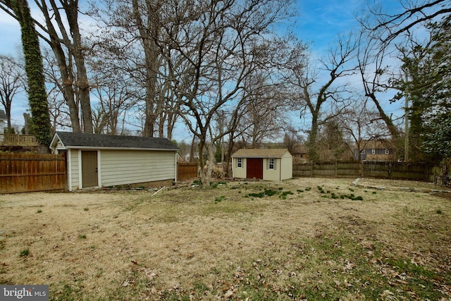 view of yard with a fenced backyard, an outbuilding, and a storage shed