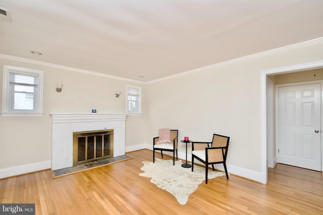 living area with crown molding, baseboards, a fireplace, and hardwood / wood-style flooring