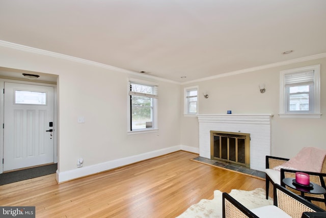 unfurnished living room with a brick fireplace, baseboards, ornamental molding, and wood finished floors