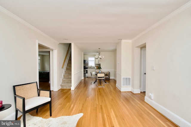 living area with stairs, a notable chandelier, visible vents, and light wood-style floors