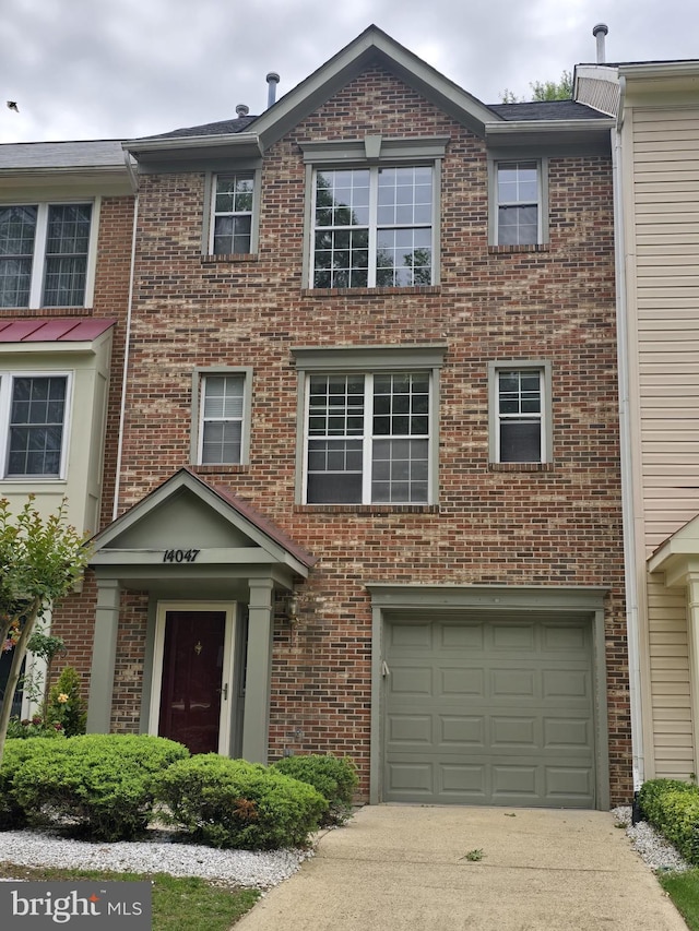 view of property with an attached garage, brick siding, and driveway