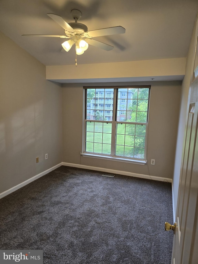 empty room featuring dark carpet, baseboards, and ceiling fan