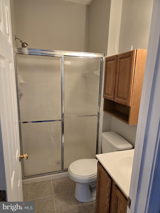 bathroom featuring tile patterned floors, a stall shower, toilet, and vanity