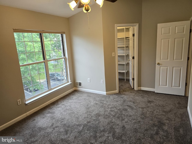unfurnished bedroom featuring carpet floors, a walk in closet, baseboards, and a closet