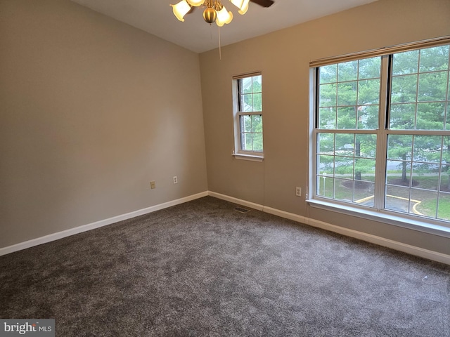 empty room featuring dark colored carpet, baseboards, and ceiling fan