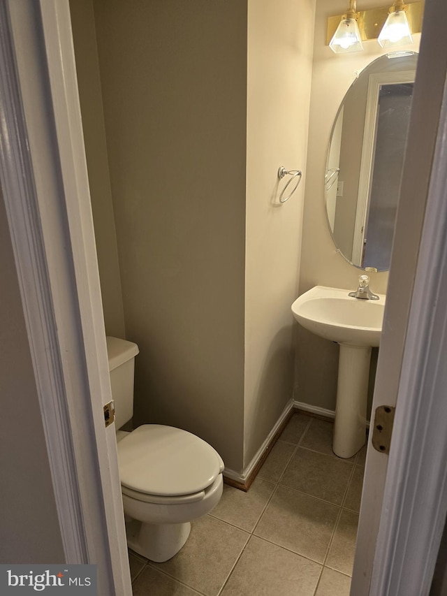 bathroom with tile patterned floors, toilet, baseboards, and a sink