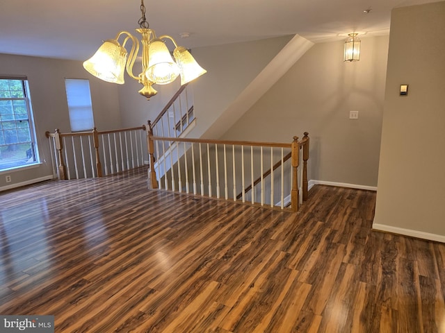 spare room with a chandelier, wood finished floors, and baseboards