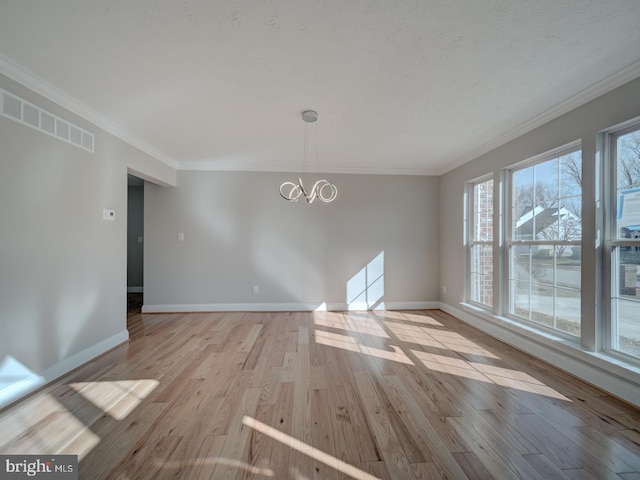 unfurnished dining area with a chandelier, light wood finished floors, baseboards, and crown molding