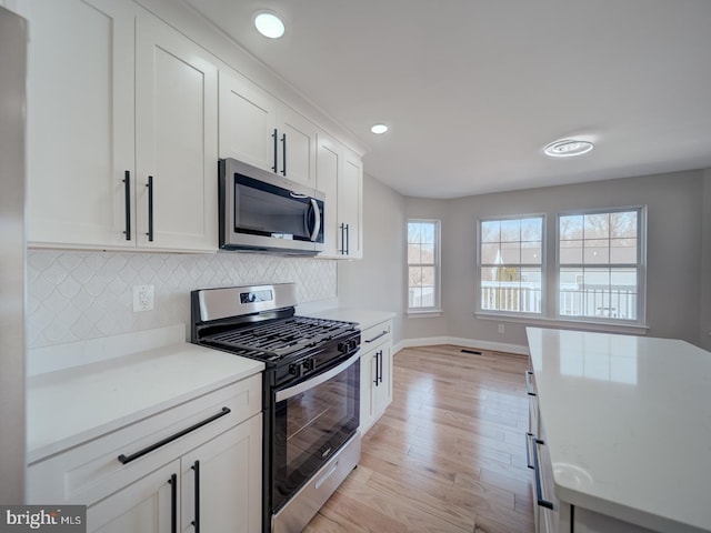 kitchen featuring appliances with stainless steel finishes, light wood-style floors, backsplash, light countertops, and recessed lighting