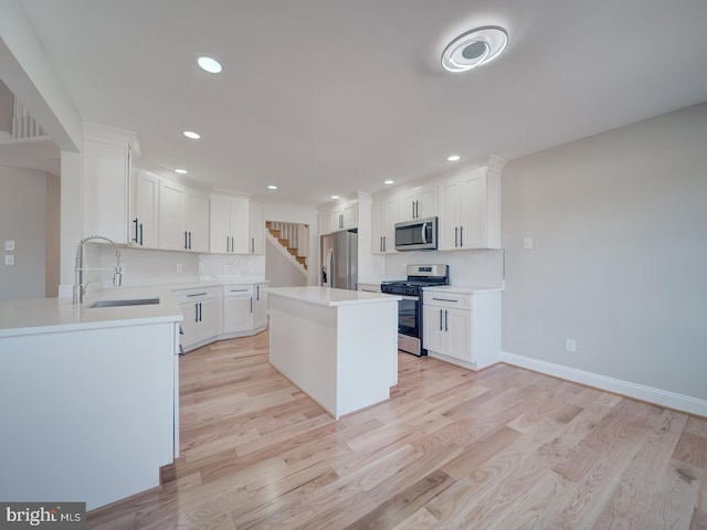 kitchen with stainless steel appliances, a sink, a center island, recessed lighting, and light wood-style floors
