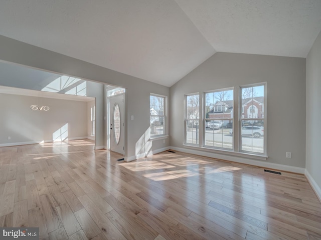 unfurnished living room featuring wood finished floors, vaulted ceiling, and baseboards