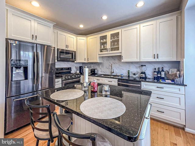 kitchen featuring appliances with stainless steel finishes, a sink, recessed lighting, tasteful backsplash, and a breakfast bar area