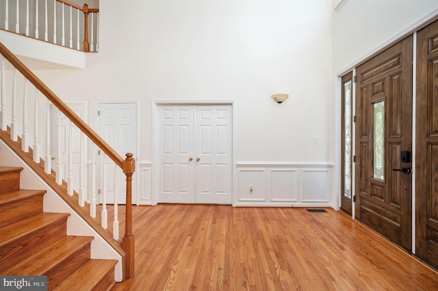 9129 Pebble Beach Ln, King George, VA 22485 - entryway featuring a high ceiling, stairway, light wood-style flooring, wainscoting, and a decorative wall