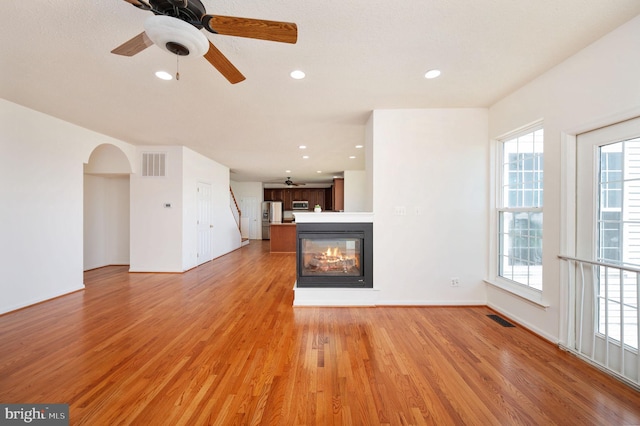 9129 Pebble Beach Ln, King George, VA 22485 - unfurnished living room featuring healthy amount of natural light, light wood-style floors, recessed lighting, a ceiling fan, and a multi sided fireplace