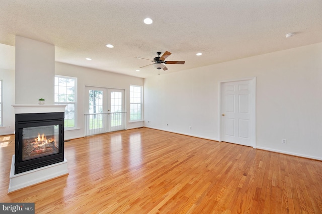 9129 Pebble Beach Ln, King George, VA 22485 - unfurnished living room with a multi sided fireplace, light wood-style flooring, a textured ceiling, recessed lighting, and a ceiling fan