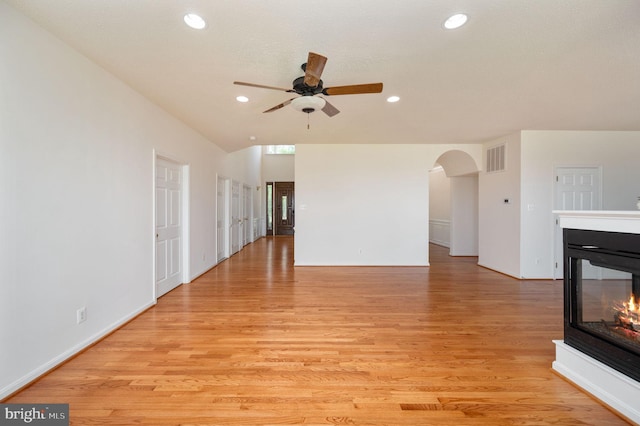 9129 Pebble Beach Ln, King George, VA 22485 - unfurnished living room featuring a multi sided fireplace, a ceiling fan, light wood finished floors, arched walkways, and recessed lighting